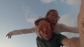 Couple taking cool selfies on the beach  in Hawaii piggy back. Young people travelling taking selfies. Slow motion 