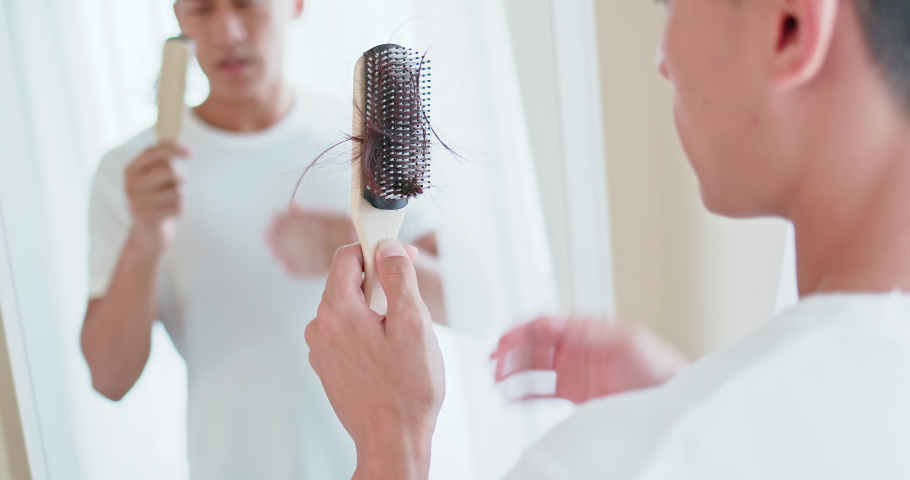 Asian man worry about his receding hairline and look in mirror with many hair on hairbrush Royalty-Free Stock Footage #1043425426