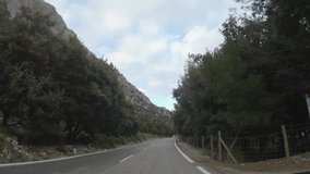 4K POV footage of car driving on rural road through beautiful mountain landscape and olive plantations. Traveling by countryside. Mediterranean scenery. Mallorca island, Spain. Point of view shot