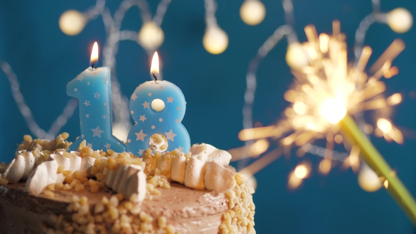 Birthday cake with 18 number candle and sparkler on blue backgraund. Slow motion and close-up view