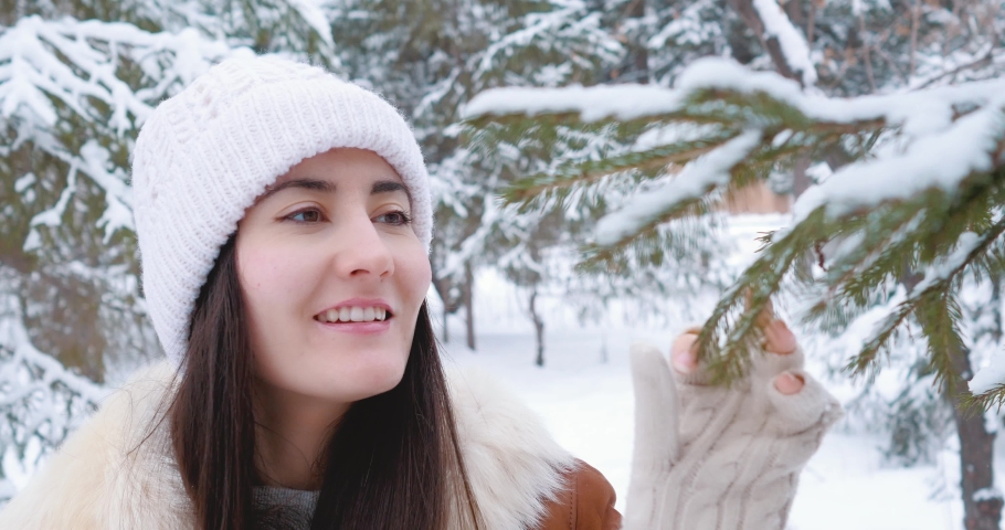 Young girl in the winter forest. Looks at the branches of a Christmas tree