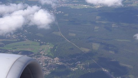 View from the plane window. Flying in an airplane over cities, lakes, forests. In the frame at the beginning, the engine of the aircraft, then slowly and smoothly rises to the horizon above the clouds