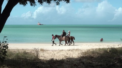 St. John's, Antigua and Barbuda / West Indies - December 2019: Horse back ride on the Runaway Beach. Couple of tourists with the guide. beautiful sunny afternoon.