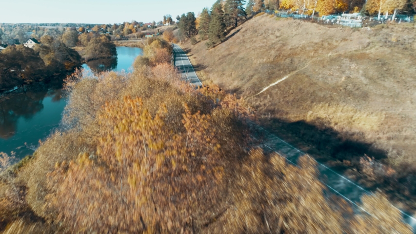 The car rides on the road near the river in the summer time.Russia
