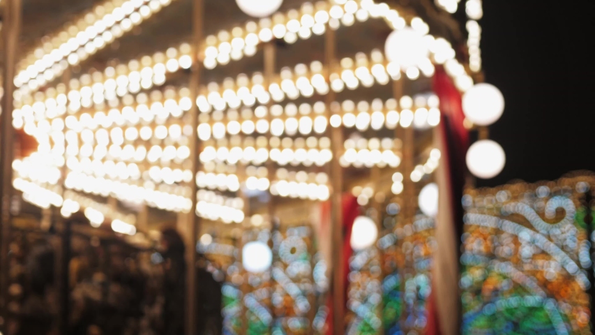 Christmas carousel. Bright carousel with lights and horses rolls the children. The frame is out of focus for background. Christmas night.
