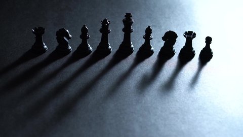 Shot of black chess pieces with dramatic light moving and creating moving dramatic shadows - 4K
