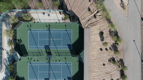 Tennis players practice singles and doubles tennis games in blue tennis fields, Aerial drone top down shot of people having fun playing tennis matches in the local club