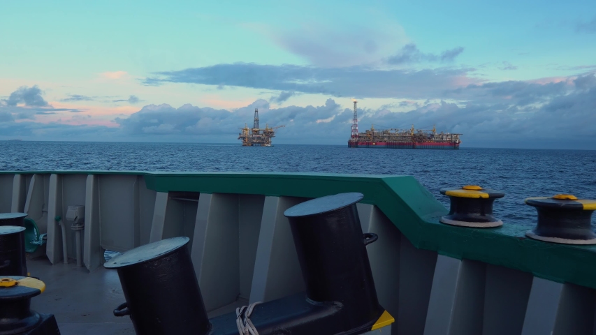 FPSO tanker vessel near Oil Rig platform. Offshore oil and gas industry. Flare is burning with smoke. View from supply vessel.