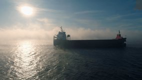 Aerial view of cargo container  ship sails in sea fog, crane vessel working for delivery of delivery containers