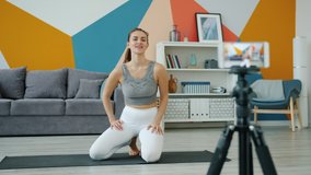 Yoga instructor vlogger is making video for online vlog using smartphone camera demonstrating balancing asana on arms. Vlogging and sports concept.