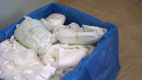 Mother throws dirty diapers into the trash. Disposing of used nappies
