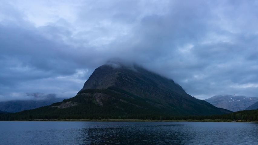 Time Lapse of Beautiful View of the reflection in the water during a cloudy morning sunrise in the American Rockies. Taken in Swiftcurrent Lake, Glacier National Park, Montana, United States.