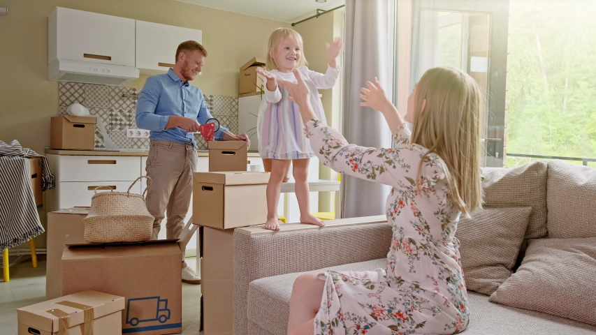 Active Family Group Move in Rent Real Estate. Positive Looking at Relocating or Unpacking of Carton Pack by Playful Family. Little girl jumps on hands to mom. Enjoying Life or Dream of Small Child by Royalty-Free Stock Footage #1043564242