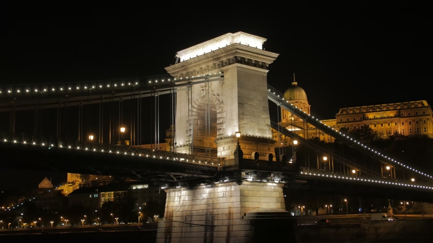 Old illuminated bridge at night Szechenyi Chain Bridge Budapest Hungary view from the river Danube tracking camera movement closeup