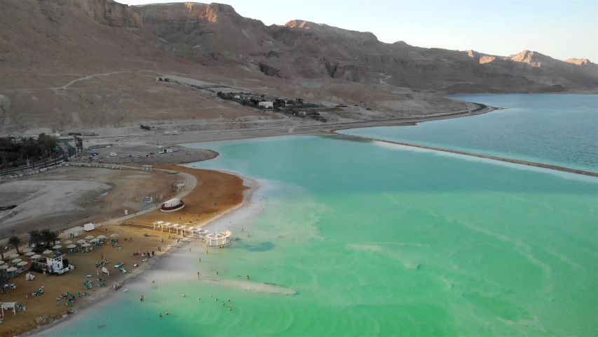 Aerial footage over Beach with People bathing and swim at Dead Sea
Drone view over Dead Sea with People bathes and swims at sunset
