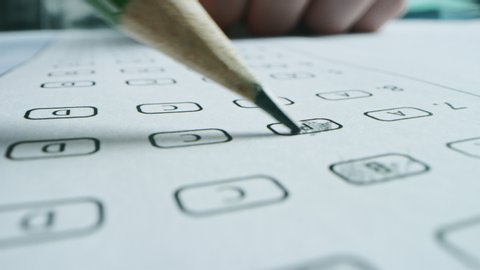 On Exam Test Person Colors Right Answers with a Pencil. Filling up Answer Sheet with Standardized Tests, Marking Correct Answer Bubbles. Macro Close-up Footage