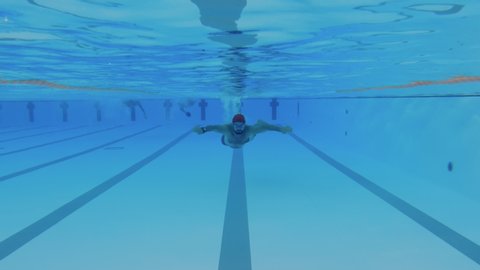 Underwater shot of professional swimmer performing breaststroke during training in swimming pool. Slow motion in 4K