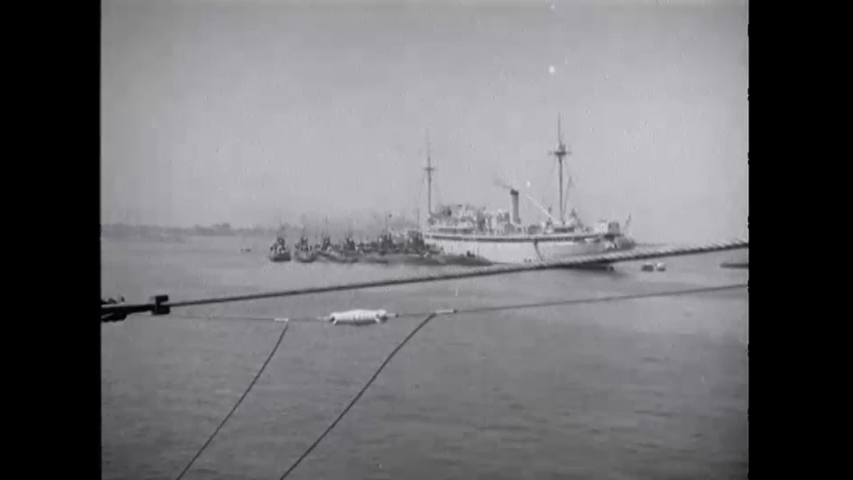 CIRCA 1948 - A fleet of old-fashioned submarines is seen sailing by a warship.