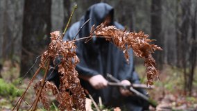 Branches of dried fern against the background of a Monk in a black robe spreading a fire in the forest, defocusing - Powered by Shutterstock - Get 15% off with code: PIKWIZARD15