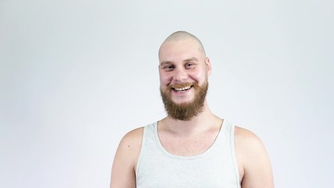 The man with the beard touches his bald head and smiling.