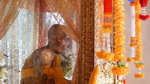 KOH SAMUI ISLAND, THAILAND - 17 JULY 2019: Wat Khiri Wongkaram Buddhist Temple. The mummified body of monk and gold leaf. Exotic tradition of storing the relics of saints who died during meditation