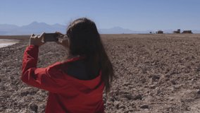 Woman in red vest taking picture with her cell phone in Laguna Cejar, Chile, Atacama