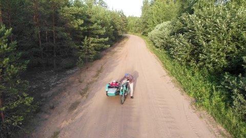 Sidecar retro turquoise motorcycle man kickstarts and rides with girl on unpaved road aerial high angle kid and parent happy childhood