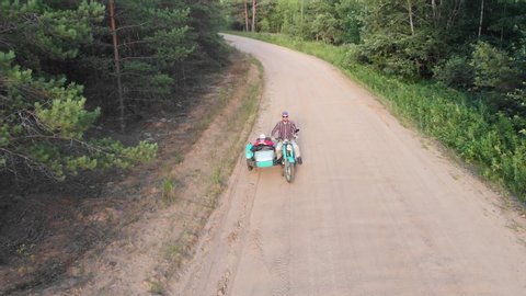 Sidecar retro turquoise motorcycle man and girl ride on unpaved road aerial high angle follow kid and parent happy childhood