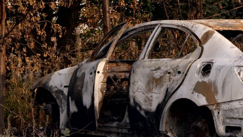 The car after the fire. Burnt passenger car Closeup. Burnt car frame with ash and garbage after a fire. Rusty steel and metal structures. Broken glass. Traffic accident and vandalism concept. 4K.
