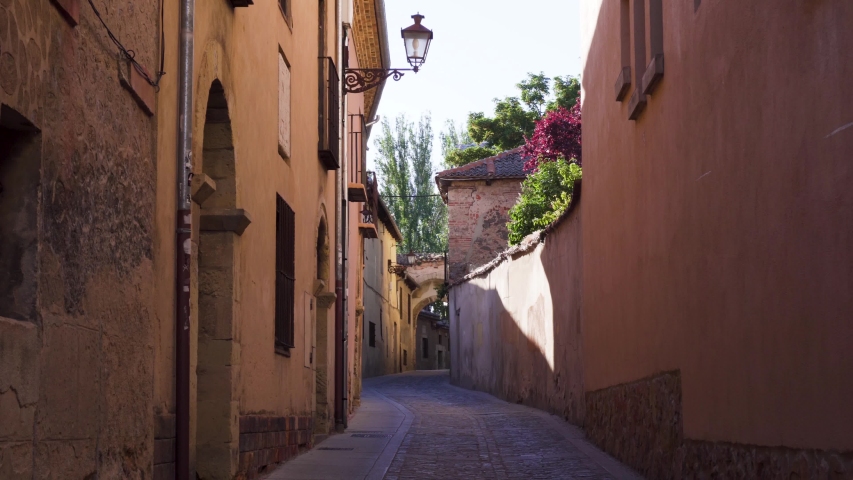 A pretty narrow street in an ancient historic Spanish town with traditional street lamp and cobble stone road.