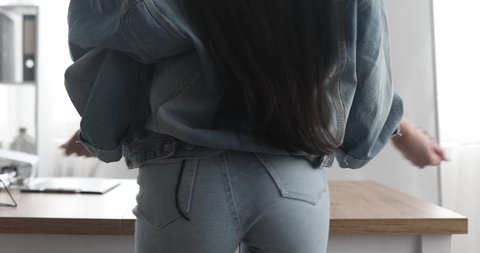Sexy brunette woman in jeans dancing. Fit buttocks. Long hair.