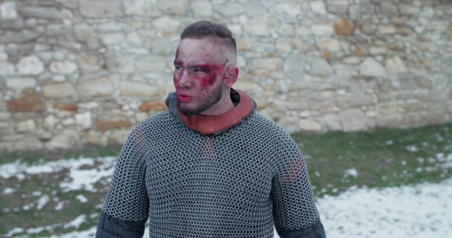 Portrait of wounded warrior juggles with sword at fortress. Slowly in 4K