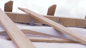 Close up of unfinished wooden roof of a new house at construction site with white protective cloth waving in the wind, carpentry concept. Clip. Parts of new ecological building.