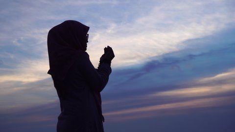 Silhouette of Female Muslim praying during sunset time