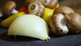 static video of fresh natural raw vegetarian ingredients used in preparation of a vegan meal to start a healthy lifestyle the organic onions mushrooms and bell peppers are vibrant and delicious.