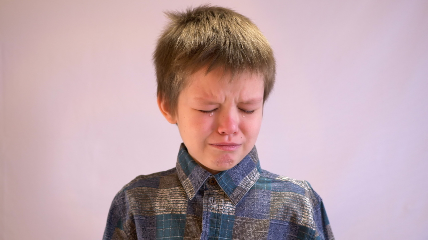 Face of crying boy close up. Eyes, eyelashes, eyebrows, lips, teeth and tears. Emotions and grimaces of upset child