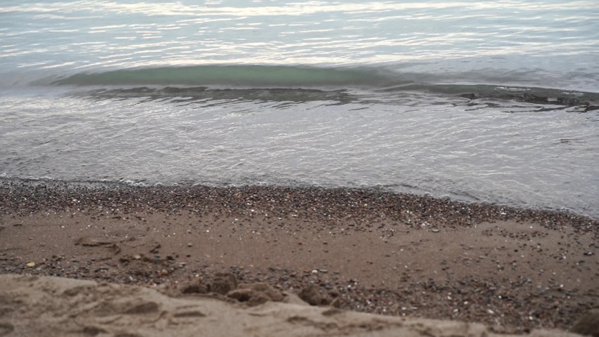 Water splashing against the shoreline of Lake Erie. View from Presque Isle in Erie, Pennsylvania. Sand, stone, water, waves.