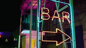 Neon bar sign medium shot . Night exterior video footage of vintage neon sign. A nighttime exterior shot of a generic, unbranded bar and restaurant in street . Gimbal shot .
