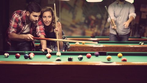 happy young people enjoying billiard game together