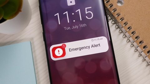Smartphone showing an emergency notification banner appearing on the lock screen. Mobile phone alert warning.
