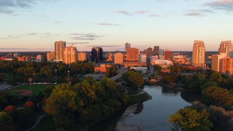 Cinematic aerial flying over Thames river with view downtown London Ontario during golden hour sunset