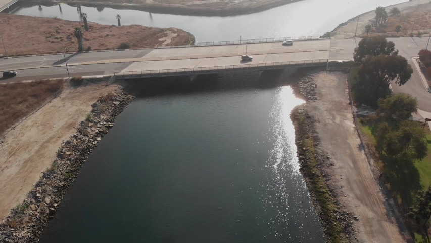 Slow aerial push toward Long Beach CA bridge with autos and blue canal