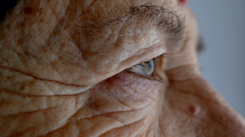 The face and eyes of an old man. Large wrinkles on the face of an old woman. Face close up. A senior citizen looks into the distance. | Shutterstock HD Video #1043693047