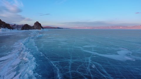 Frozen lake Baikal, Cape Burhan Shaman rock near the village of Khuzhir, Olkhon island. Beautiful winter landscape. Famous natural landmark of Russia. Blue ice with deep cracks. (No color grading)