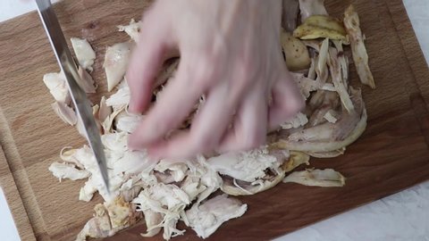 Woman cutting boned chicken on a wooden board