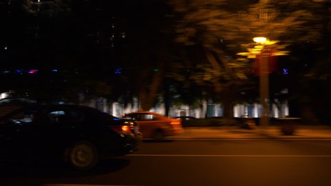 SANYA, CHINA - OCTOBER 2 2018: night time illuminated sanya city road trip passenger side pov panorama 4k circa october 2 2018 sanya, hainan china.