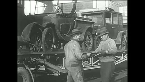 CIRCA 1920s - Henry Ford sits on the assembly line in the last Model T and Model T automobiles are scraped.