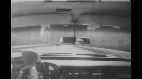 CIRCA 1958 - A man listens to the radio and gets a call on a car phone on his way to work.