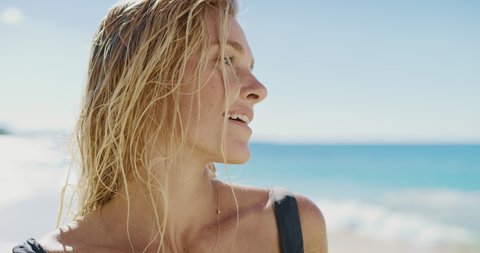 Portrait of attractive young woman smiling at the beach, happy healthy blonde woman radiating wellness and life