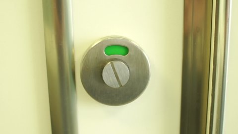 Close-up of a toilet door lock with a red closed sign switches to a green open sign. Slow motion.